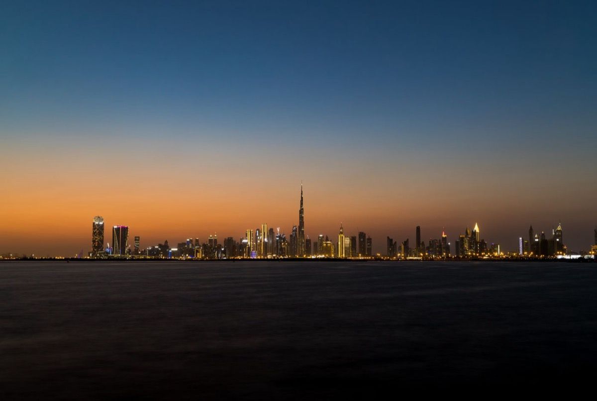 The Dubai skyline at twilight, seen across the water.