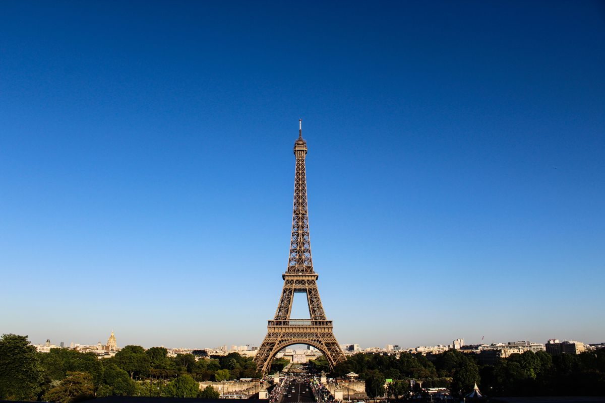 The Eiffel Tower above the Paris rooftops under a clear sky.